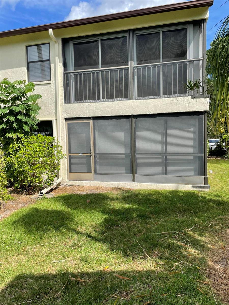A two-story building exterior features a screened-in ground floor patio and an upper balcony — 3345 Perimeter Drive # 1311, FL 33467, FL