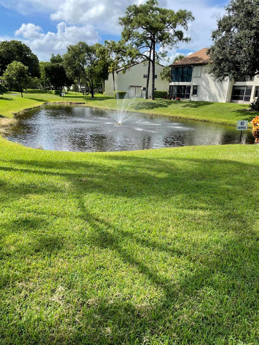 A small pond with a fountain sits in front of a multi-story residential building — 3345 Perimeter Drive # 1311, FL 33467, FL