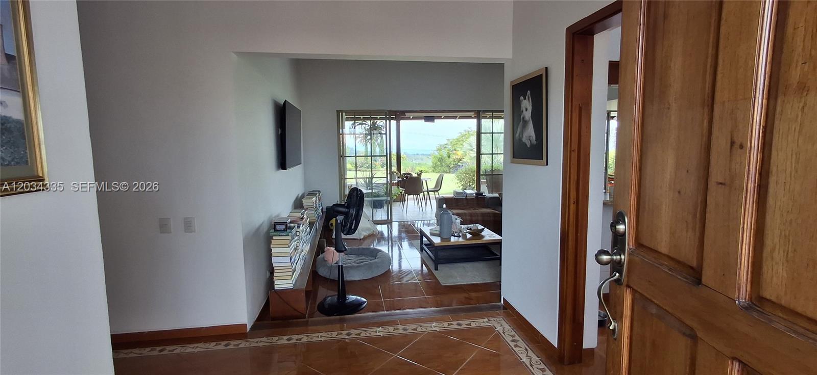 An interior view shows a tiled living area with a bookshelf and a patio beyond — Casa Campestre Via Condina Casa 19, FL 0, FL