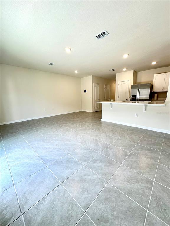 An open-concept kitchen and living area features light gray tile flooring and white cabinetry — 2349 PENGUIN BOULEVARD, DAVENPORT, FL