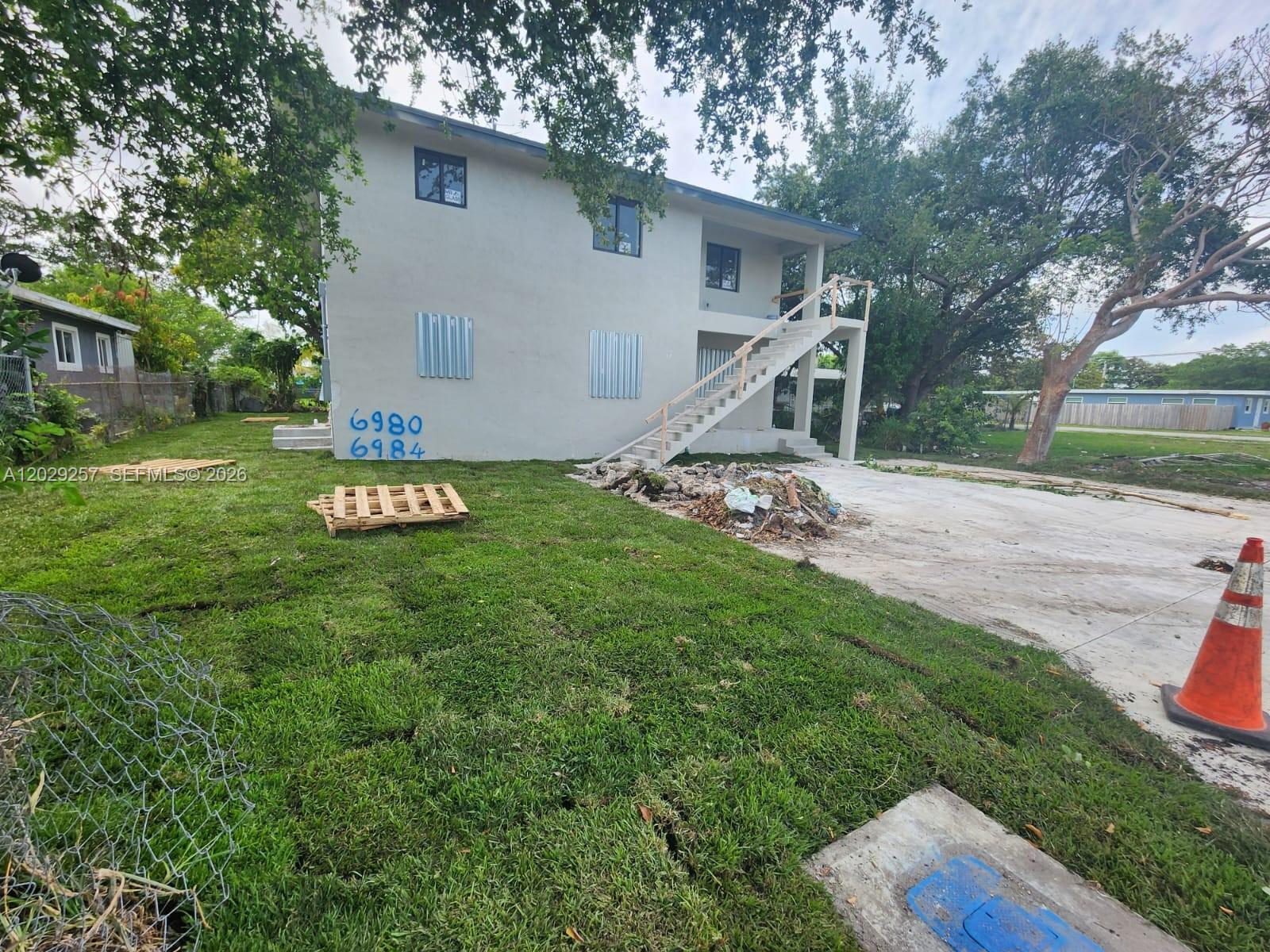 A two-story building exterior features a concrete staircase, metal shutters, and a grassy yard — 2970 NW 48th St # 2970, Miami FL 33142, MIAMI, FL