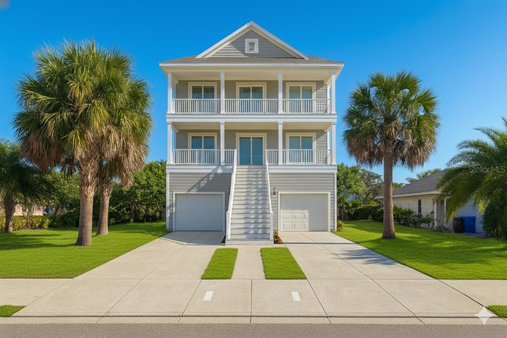 A three-story elevated house with two garage doors, a central staircase, and two balconies — 6225 FLAMINGO DRIVE, APOLLO BEACH, FL