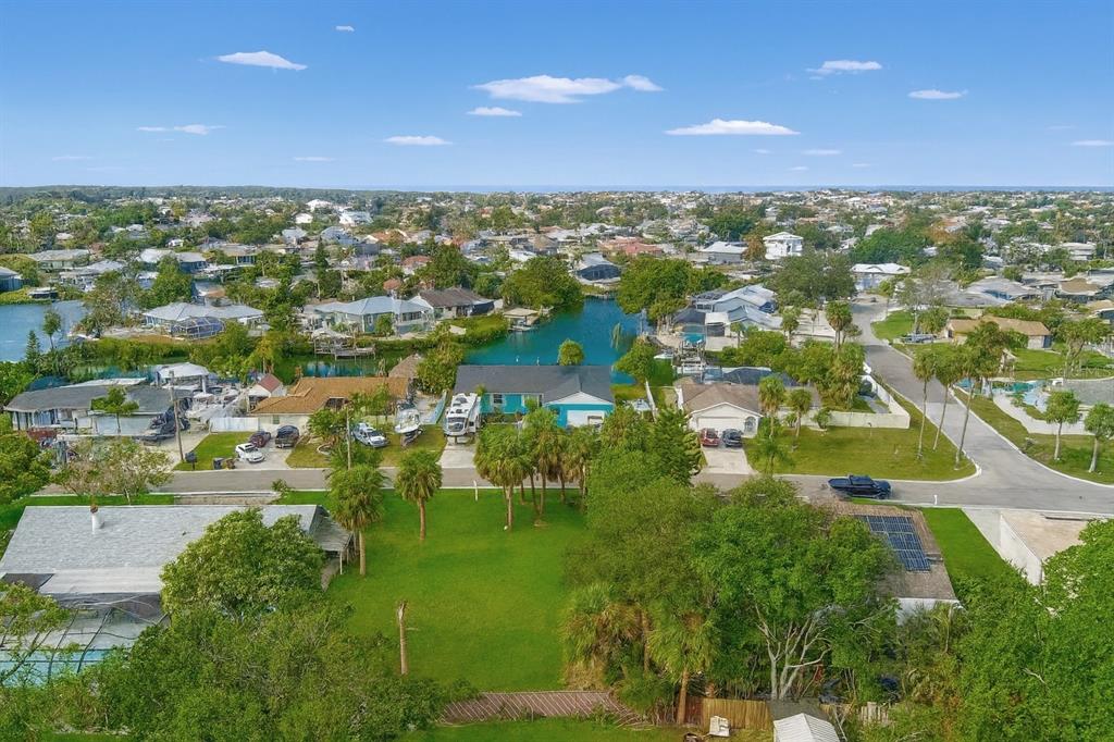 An aerial view shows a residential neighborhood with a canal, houses, and green lawns — 6225 FLAMINGO DRIVE, APOLLO BEACH, FL