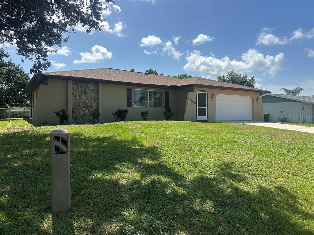 A single-story house with a stone accent wall, a two-car garage, and a grassy lawn — 4222 COCKRELL STREET, PORT CHARLOTTE, FL