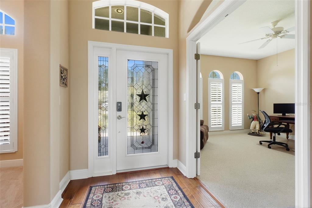An entryway features a white front door with decorative glass, wood floors, and an adjacent office — 10404 BELMULLET DRIVE, SAN ANTONIO, FL