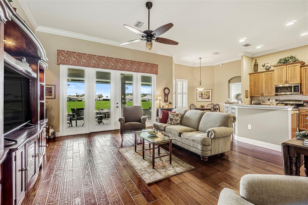 A living room with hardwood floors, a ceiling fan, and a view of a golf course — 10404 BELMULLET DRIVE, SAN ANTONIO, FL
