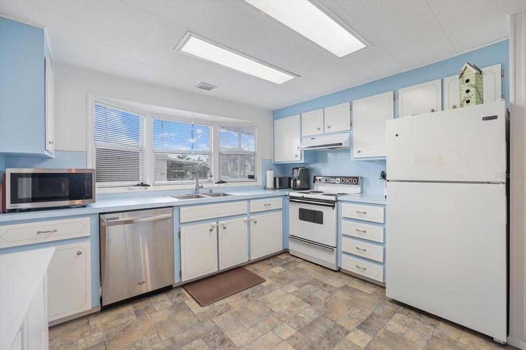 A kitchen features white cabinets, light blue walls, stainless steel appliances, and tile flooring — 832 JOLANDA CIRCLE, VENICE, FL