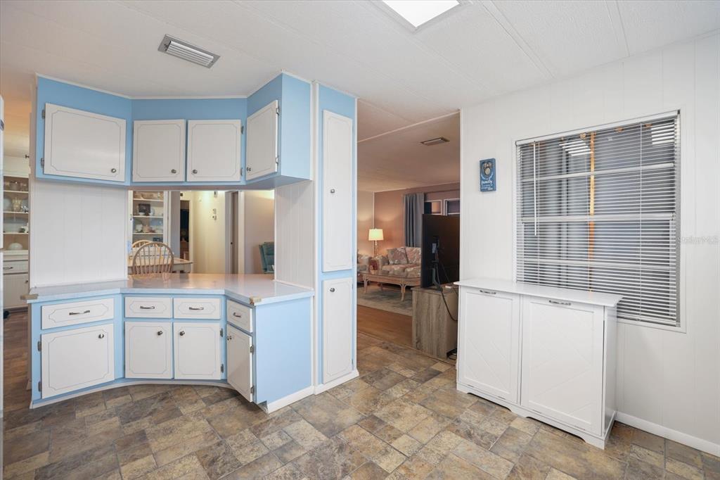 A kitchen with light blue cabinets and white countertops overlooks a living room area — 832 JOLANDA CIRCLE, VENICE, FL