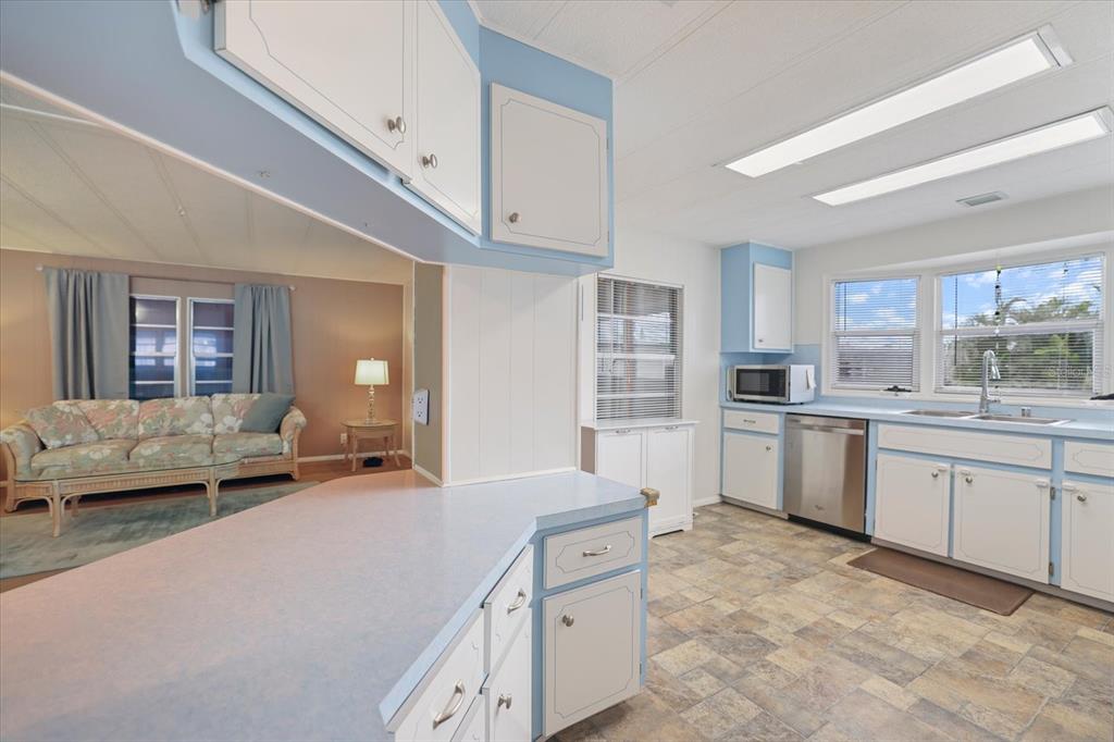 A kitchen with light blue cabinets and countertops overlooks a living room with a sofa — 832 JOLANDA CIRCLE, VENICE, FL