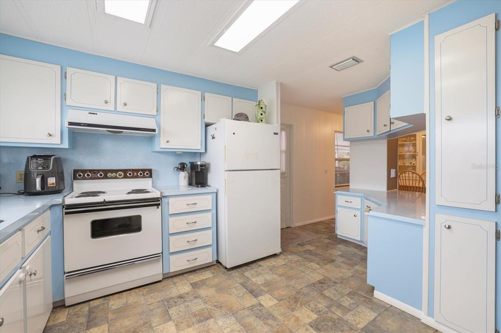 A kitchen with light blue walls, white cabinets, white appliances, and patterned vinyl flooring — 832 JOLANDA CIRCLE, VENICE, FL