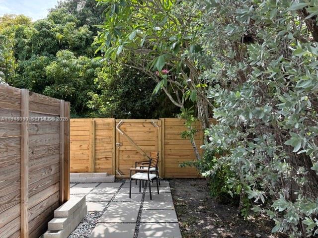 A wooden fence encloses a patio area with stone pavers and two chairs — 752 NW 24th Ct # 1, Miami FL 33125, MIAMI, FL