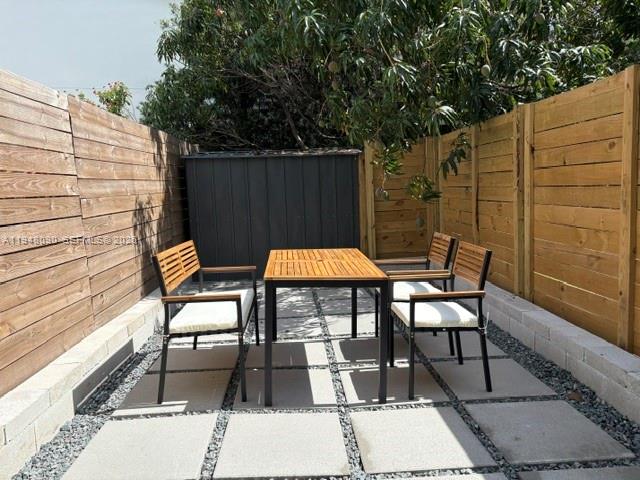 A patio features a wooden table and chairs set on concrete pavers between wooden fences — 752 NW 24th Ct # 1, Miami FL 33125, MIAMI, FL