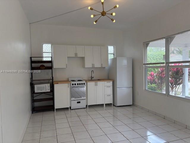 A kitchen features white cabinets, a gas stove, a refrigerator, and white tile flooring — 752 NW 24th Ct # 1, Miami FL 33125, MIAMI, FL