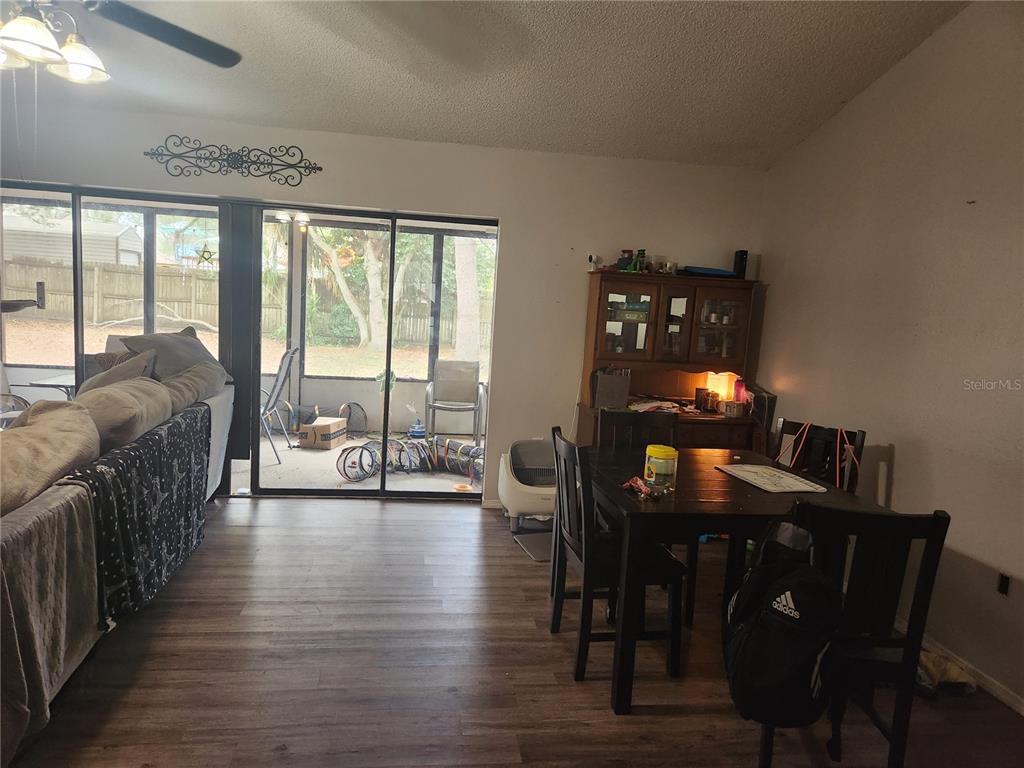 A dining area and living room with wood-look flooring lead to a screened-in patio — 6202 PIEDMONT DRIVE, SPRING HILL, FL