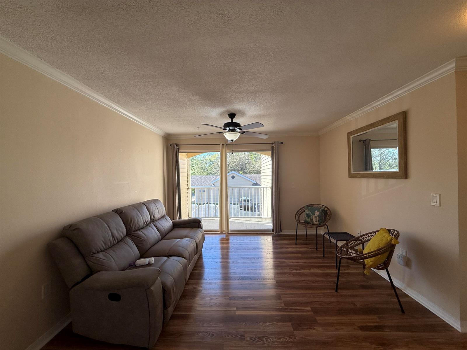 A living room features wood-look flooring, a gray sofa, two wicker chairs, and a sliding door — 1979 Summer Club Drive # 213, FL 32765, FL