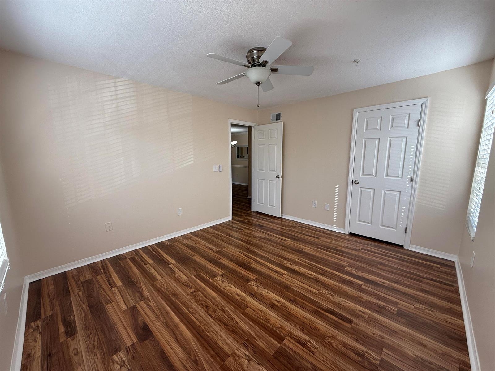 An empty room features light-colored walls, wood-look flooring, a ceiling fan, and two white doors — 1979 Summer Club Drive # 213, FL 32765, FL