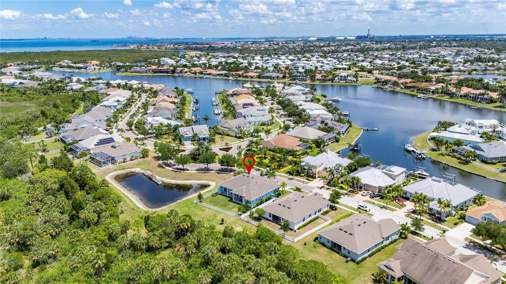 An aerial view shows a residential neighborhood with houses, canals, and surrounding greenery — 638 MANNS HARBOR DRIVE, APOLLO BEACH, FL