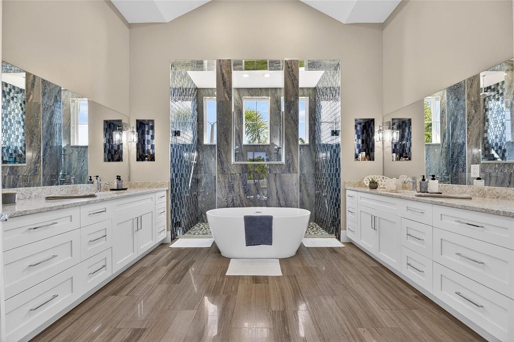 A symmetrical primary bathroom features a freestanding tub, dual vanities, and blue-toned stone tile accents — 638 MANNS HARBOR DRIVE, APOLLO BEACH, FL