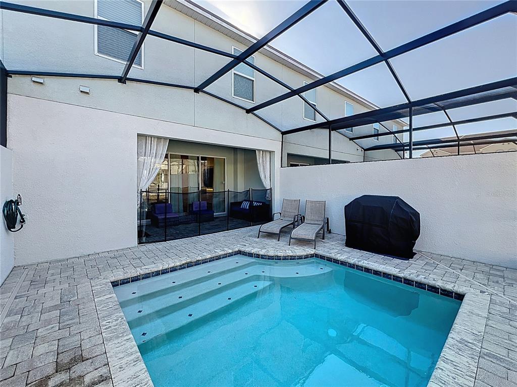A screened-in patio features a small swimming pool, lounge chairs, and a covered grill — 1800 TROPICAL PALMS CIRCLE, KISSIMMEE, FL