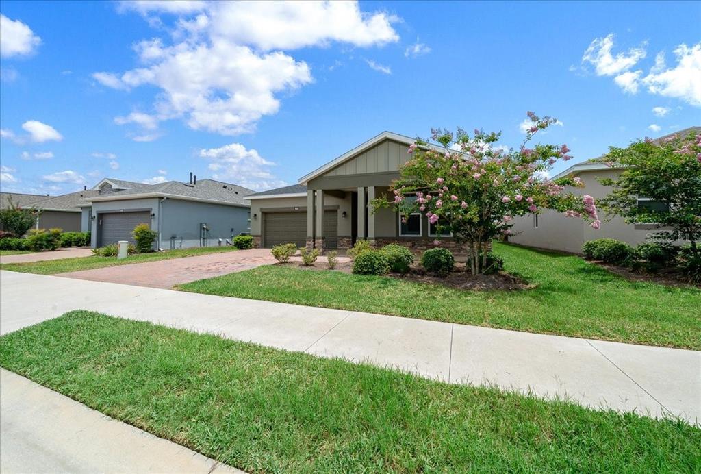 A single-story suburban house with a paved driveway, green lawn, and a flowering tree — 4351 NW 54TH TERRACE, OCALA, FL