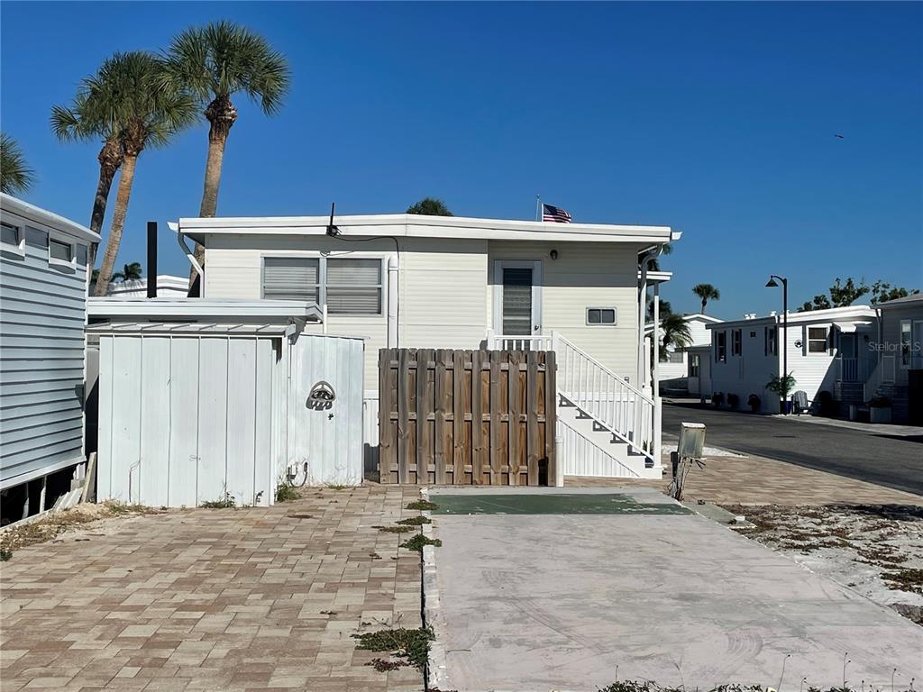 An exterior view of a mobile home with a wooden privacy fence and paved driveway — 3710 GULF OF MEXICO DRIVE UNIT D11, LONGBOAT KEY, FL