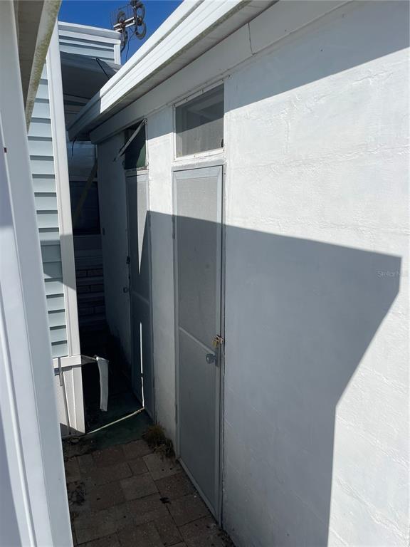 A narrow exterior walkway leads to two white doors on a concrete block building — 3710 GULF OF MEXICO DRIVE UNIT D11, LONGBOAT KEY, FL
