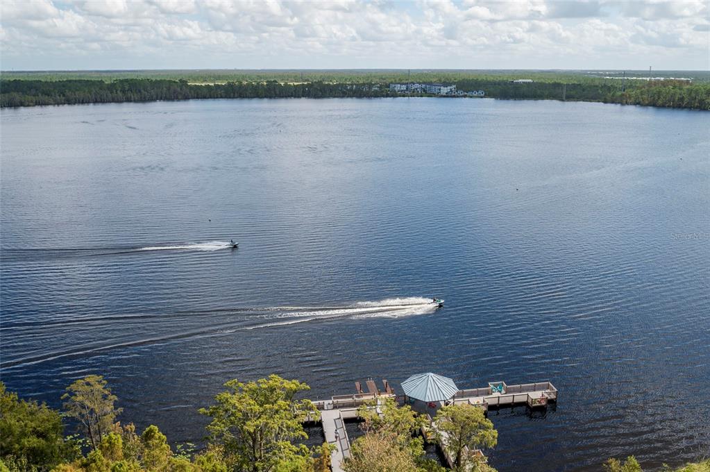 An aerial view shows a lake with two jet skis and a wooden boat dock — 13415 BLUE HERON BEACH DRIVE UNIT 1404, ORLANDO, FL