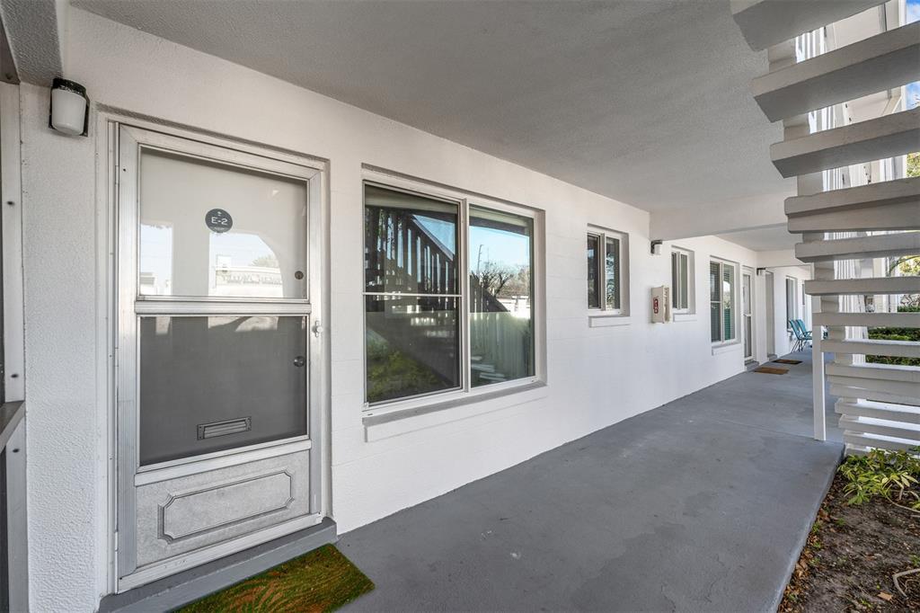 A ground-level apartment entrance features a screen door, a large window, and exterior stairs — 1140 S ORLANDO AVENUE UNIT E2, MAITLAND, FL