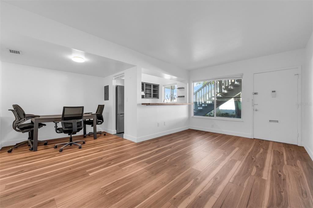 A bright room with wood-look flooring, a desk area, a pass-through window, and an exterior door — 1140 S ORLANDO AVENUE UNIT E2, MAITLAND, FL