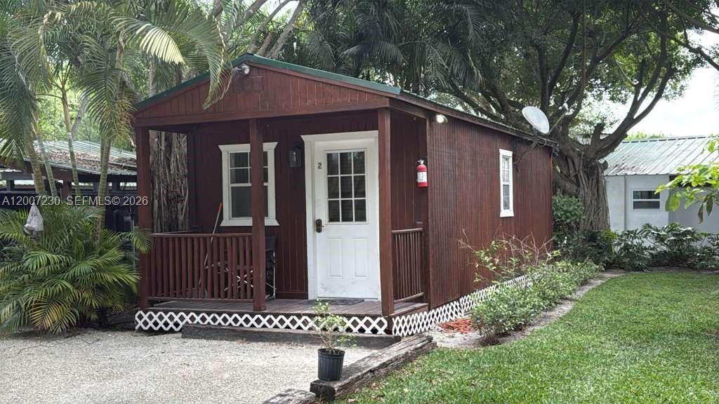 A small, brown wooden cabin with a front porch, white door, and lattice skirting — 14996 50th St S, Wellington FL 33414, WELLINGTON, FL