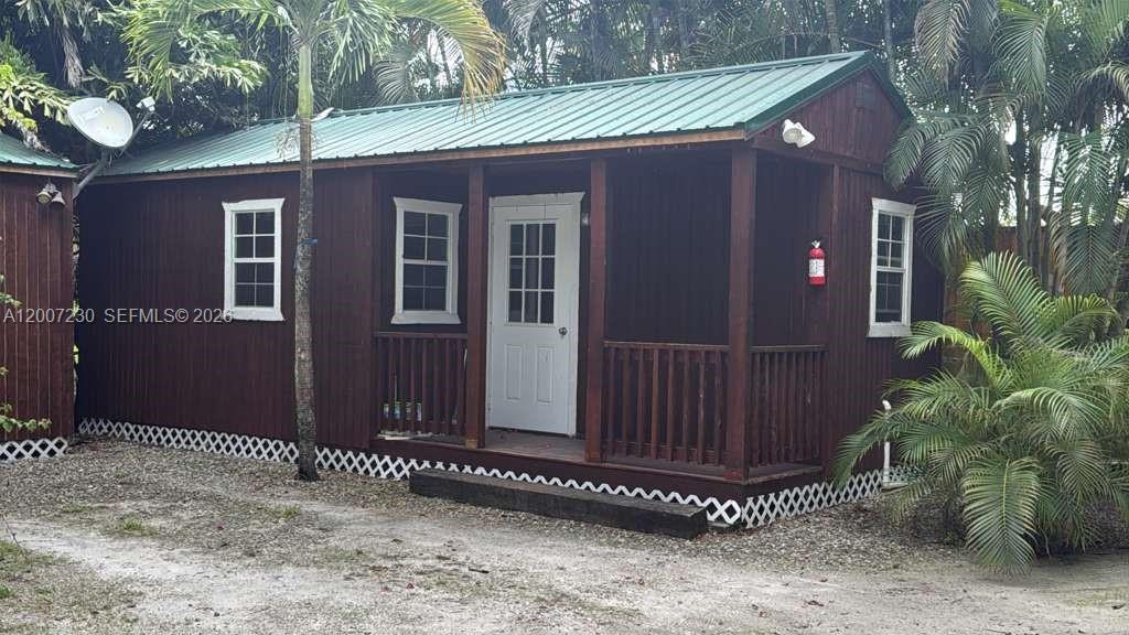 A small, brown wooden cabin with a green metal roof and a front porch — 14996 50th St S, Wellington FL 33414, WELLINGTON, FL