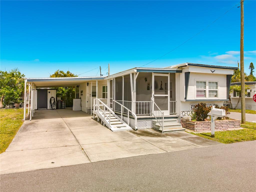 A single-story mobile home with a carport, screened-in porch, and a concrete driveway — 800 32ND AVENUE S UNIT 727, ST PETERSBURG, FL