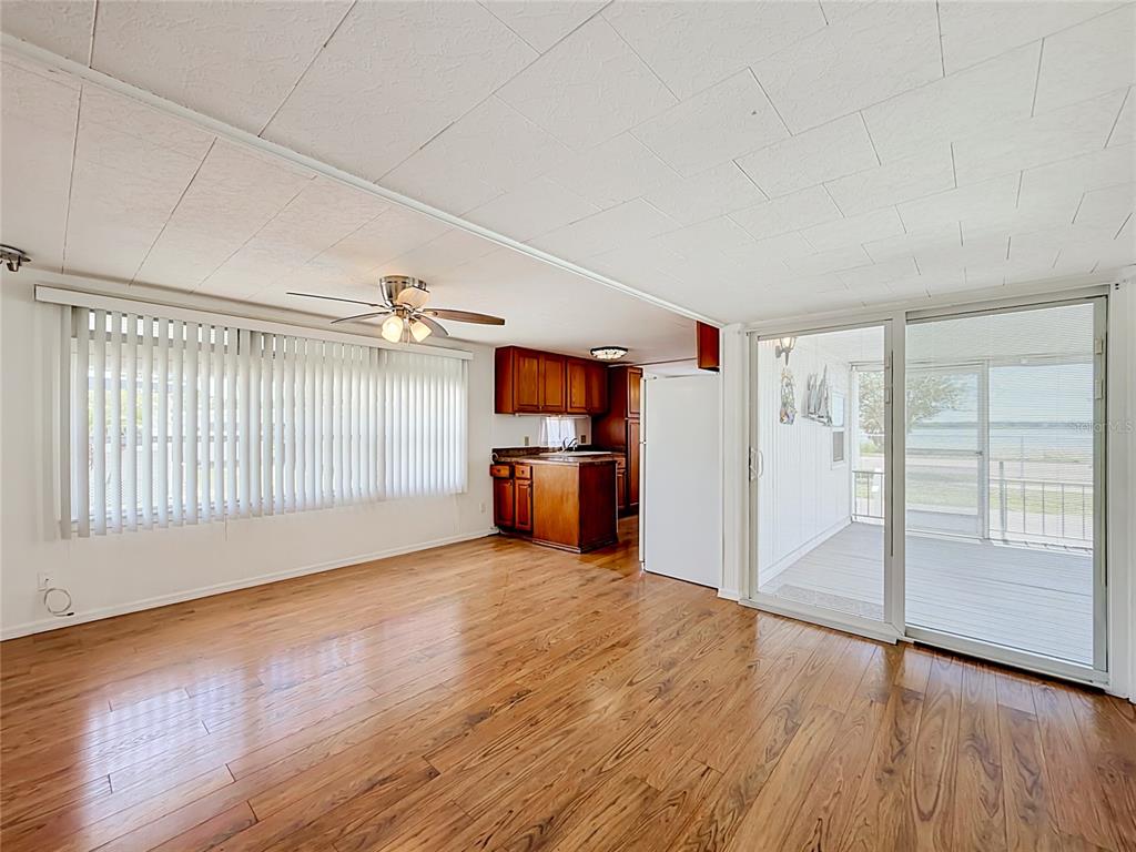 A living room with wood-look flooring, a ceiling fan, and sliding doors to a porch — 800 32ND AVENUE S UNIT 727, ST PETERSBURG, FL