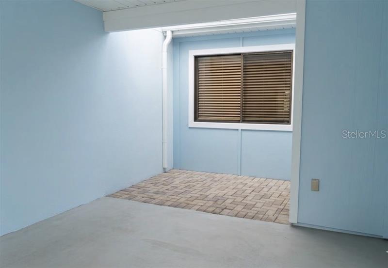 A light blue patio area features a paved section, a window with blinds, and concrete flooring — 494 PRESTWICK PLACE UNIT N/A, KISSIMMEE, FL