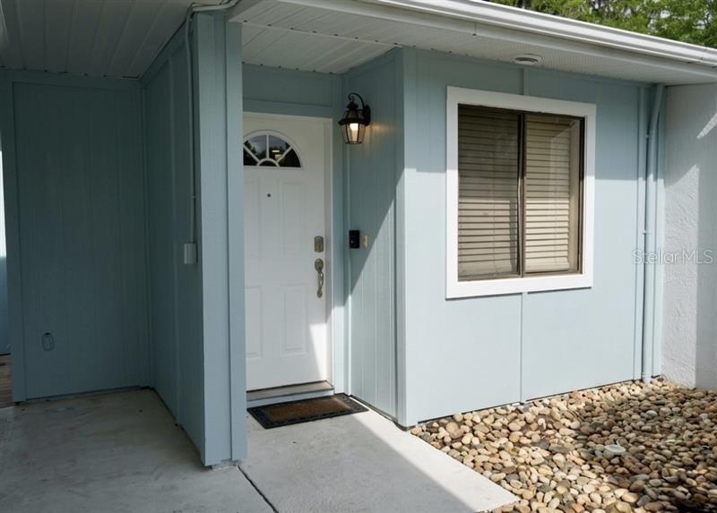 A light blue exterior wall features a white front door, a window, and a rock garden — 494 PRESTWICK PLACE UNIT N/A, KISSIMMEE, FL