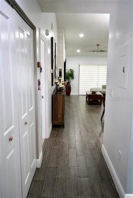 A hallway with wood-look tile flooring leads into a living room with a ceiling fan — 494 PRESTWICK PLACE UNIT N/A, KISSIMMEE, FL