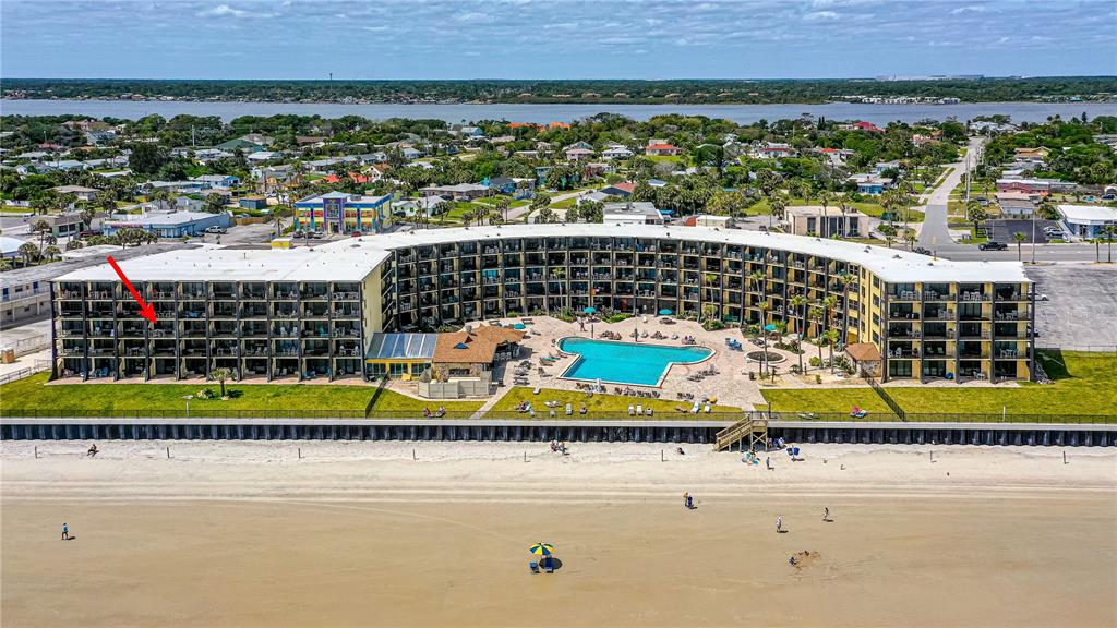An aerial view shows a curved beachfront hotel with a pool and surrounding coastal town — 2301 S ATLANTIC AVENUE UNIT 338, DAYTONA BEACH, FL
