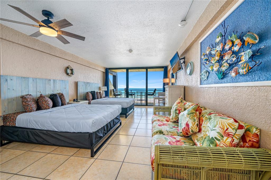 A hotel room features two beds, a floral sofa, and a balcony overlooking the ocean — 2301 S ATLANTIC AVENUE UNIT 338, DAYTONA BEACH, FL