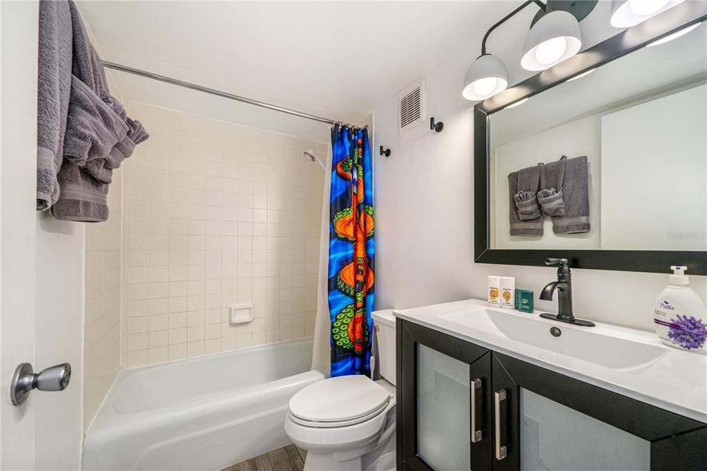 A bathroom features a tub-shower combination, a toilet, and a modern vanity with black cabinetry — 2301 S ATLANTIC AVENUE UNIT 338, DAYTONA BEACH, FL