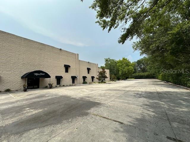 A large, beige commercial building with a black awning stands beside a paved parking lot — 2251 TOPLINE WAY UNIT 4, BROOKSVILLE, FL