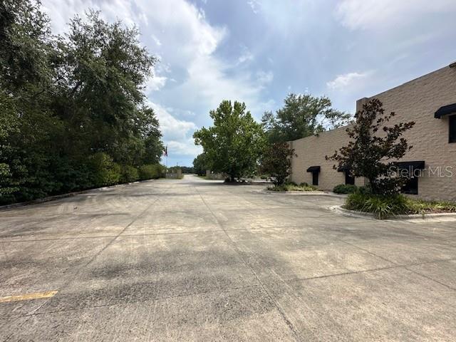A paved parking lot sits in front of a tan commercial building with mature trees — 2251 TOPLINE WAY UNIT 4, BROOKSVILLE, FL