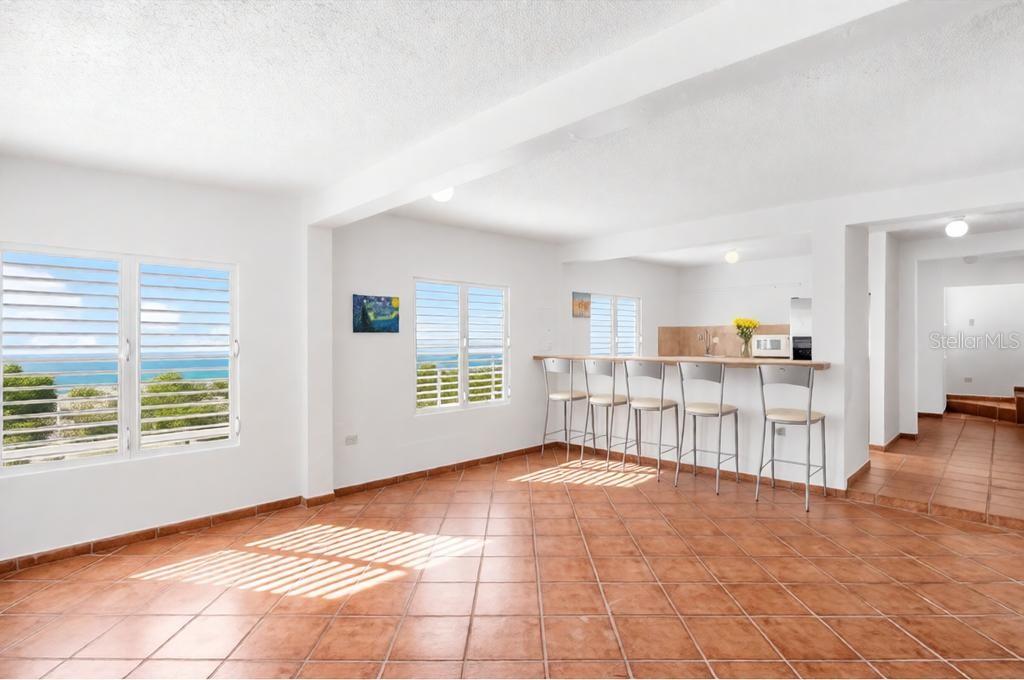 An open-concept room features terracotta tile floors, a breakfast bar with stools, and ocean views — 39 COMM PLAYA GUAYANES, YABUCOA, PR