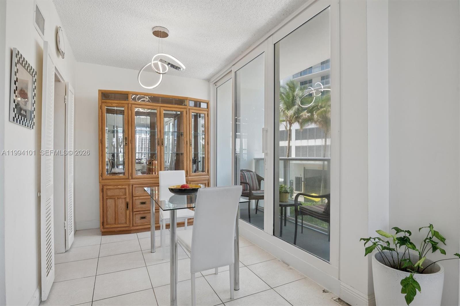 A dining area features a glass table, white chairs, a wooden hutch, and balcony access — 3505 S Ocean Dr # 201, Hollywood FL 33019, HOLLYWOOD, FL