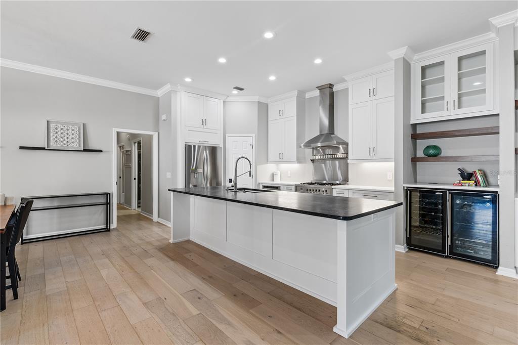 A modern kitchen features white cabinetry, a large central island, and stainless steel appliances — 3636 SW 97TH WAY, GAINESVILLE, FL
