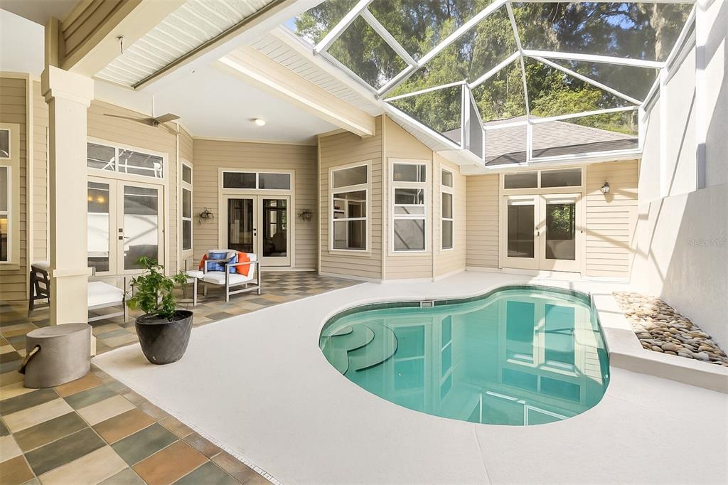 A screened-in patio features a kidney-shaped pool, tiled flooring, and multiple glass entry doors — 3636 SW 97TH WAY, GAINESVILLE, FL