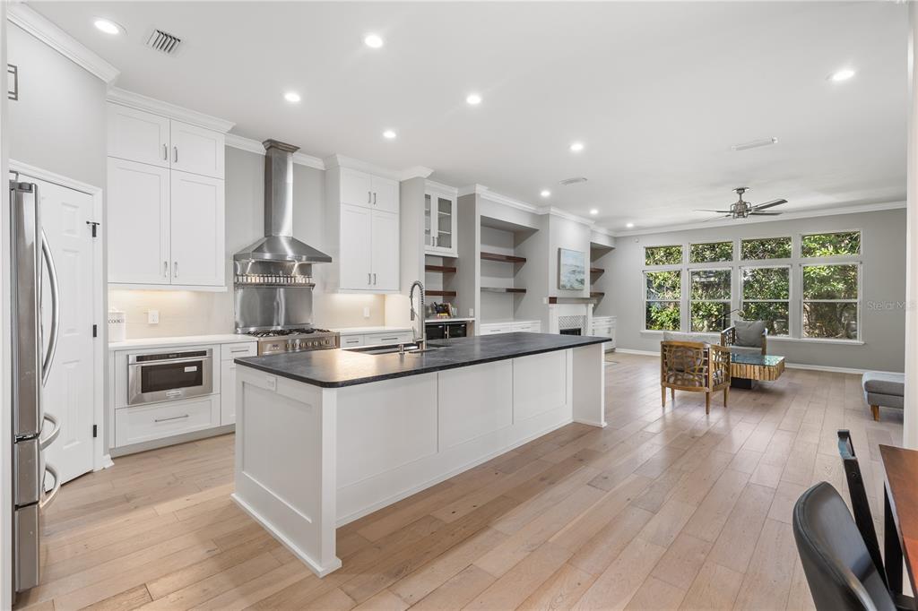 A modern kitchen with white cabinets, a dark island, and an open-concept living area — 3636 SW 97TH WAY, GAINESVILLE, FL