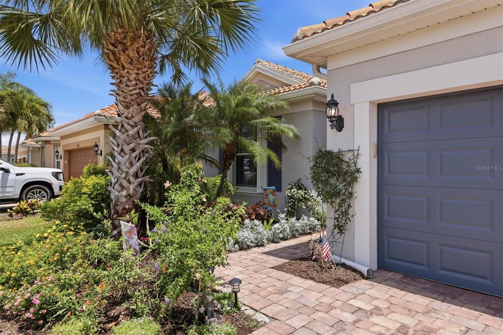 A paved walkway leads to the garage and front entrance of a house with landscaping — 19454 RIZZUTO STREET, VENICE, FL