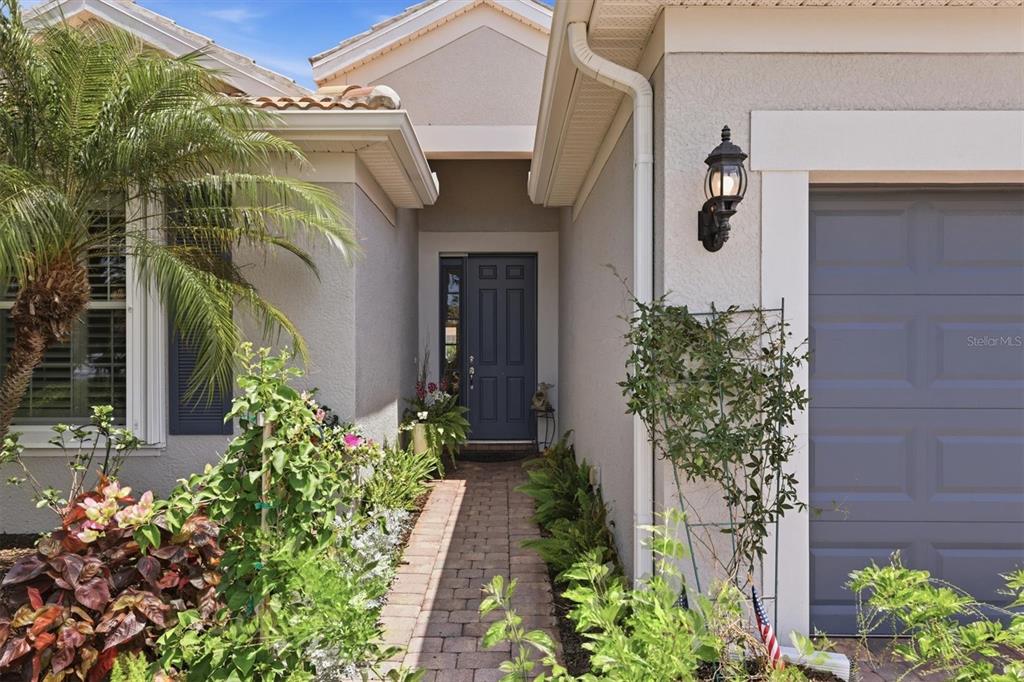 A brick walkway leads to the blue front door of a house with a garage — 19454 RIZZUTO STREET, VENICE, FL