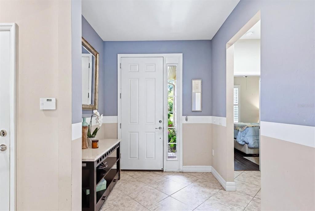 An entryway with tile flooring, a white front door, and a console table — 19454 RIZZUTO STREET, VENICE, FL