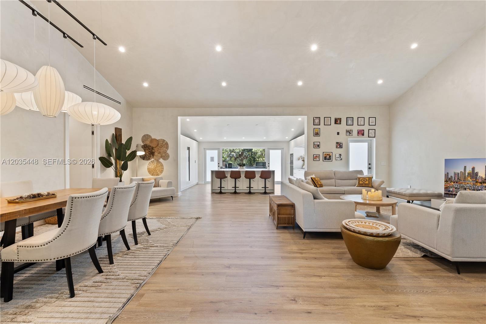 A spacious open-concept living and dining area features light wood floors and vaulted ceilings — 520 Bay Point Rd, Miami FL 33137, MIAMI, FL